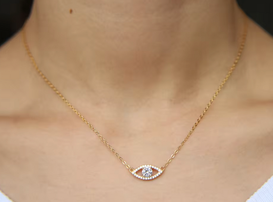 A gold necklace with a cubic zirconia evil eye pendant, featuring a curved design with multiple smaller cubic zirconia stones around the eye.