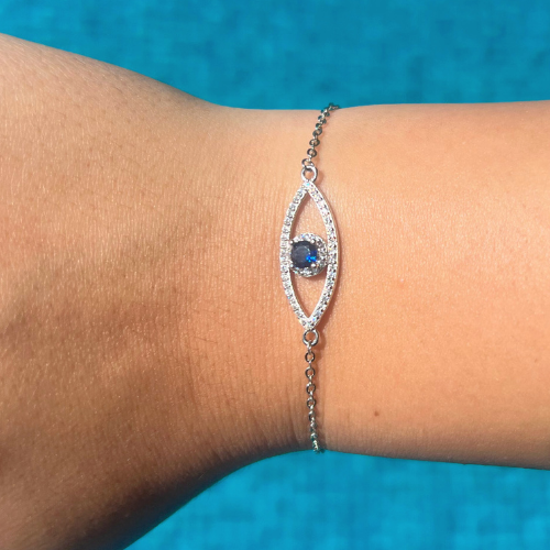 An adjustable sterling silver bracelet featuring a blue cubic zirconia evil eye charm with intricate detailing.